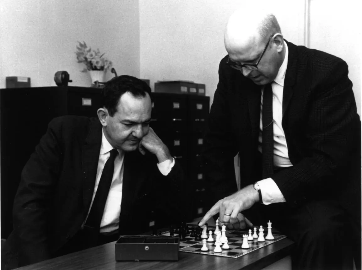 Early computing researchers studying a chess position